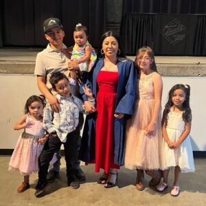 A college graduate in a graduation gown surrounded by her family