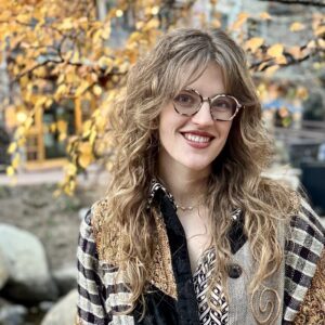 A woman with wavy dirty blonde hair and glasses