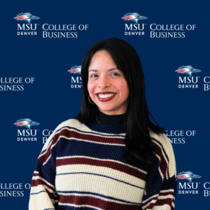 Monica Vargas - A smiling student ambassador with long, dark hair, wearing a striped top in front of an MSU Denver College of Business backdrop.