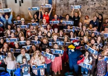 A group of social work students smiling and holding banners that read 