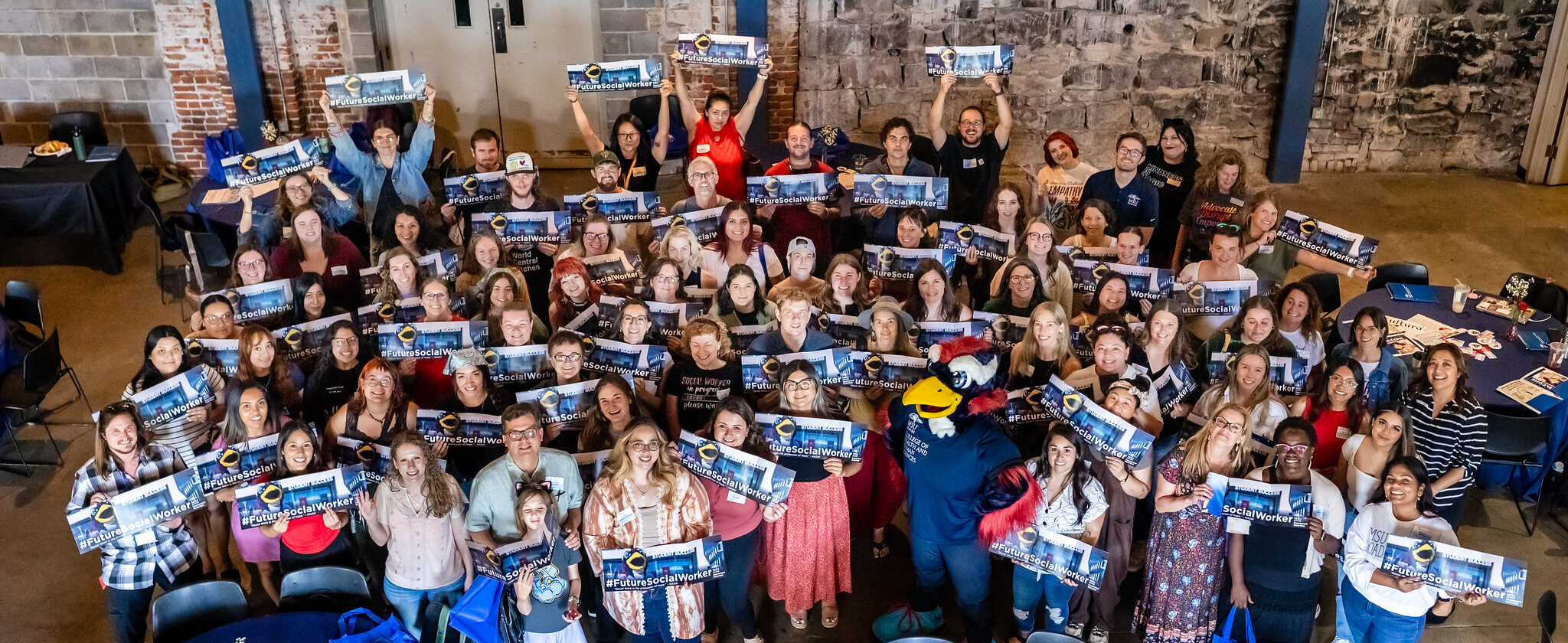 A group of social work students smiling and holding banners that read 