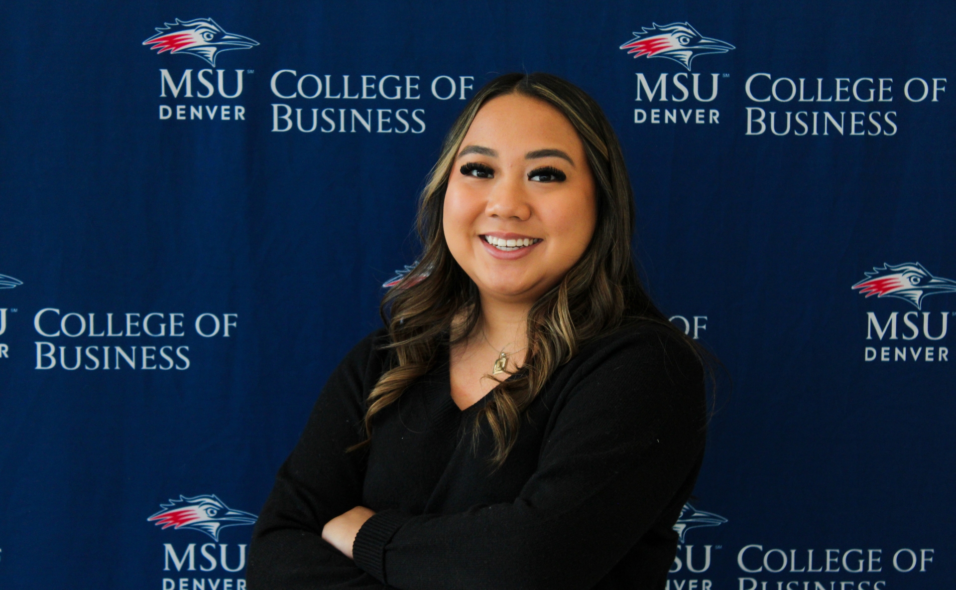 A smiling student ambassador standing in front of an MSU Denver College of Business backdrop.