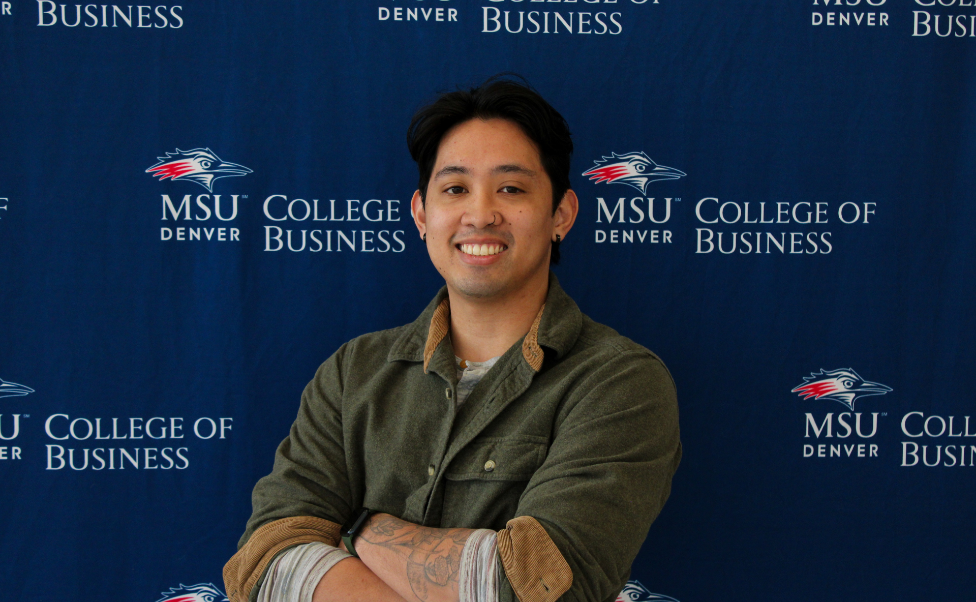 Renz Axalan - smiling student ambassador standing in front of an MSU Denver College of Business backdrop.