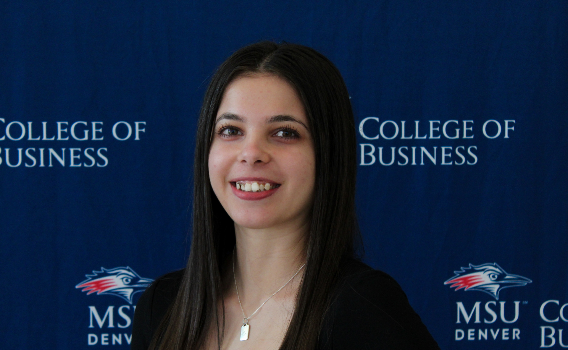 A smiling student ambassador standing in front of an MSU Denver College of Business backdrop.