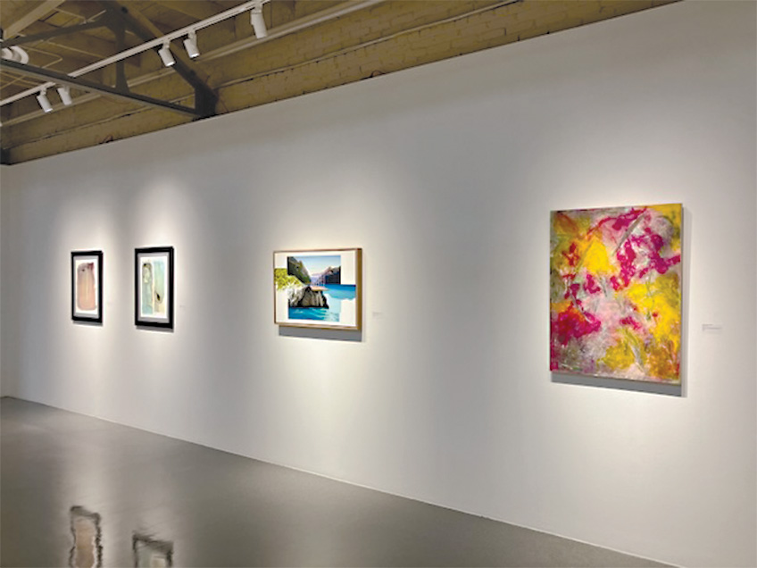 An art gallery wall displaying four paintings with a mix of abstract and landscape art.