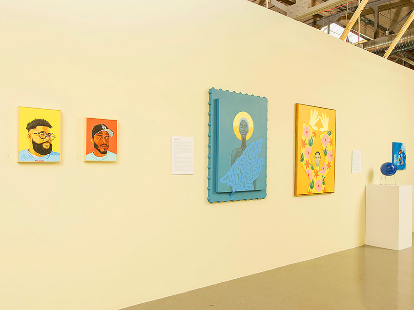 An art gallery wall displaying portraits, paintings, and a small sculpture.