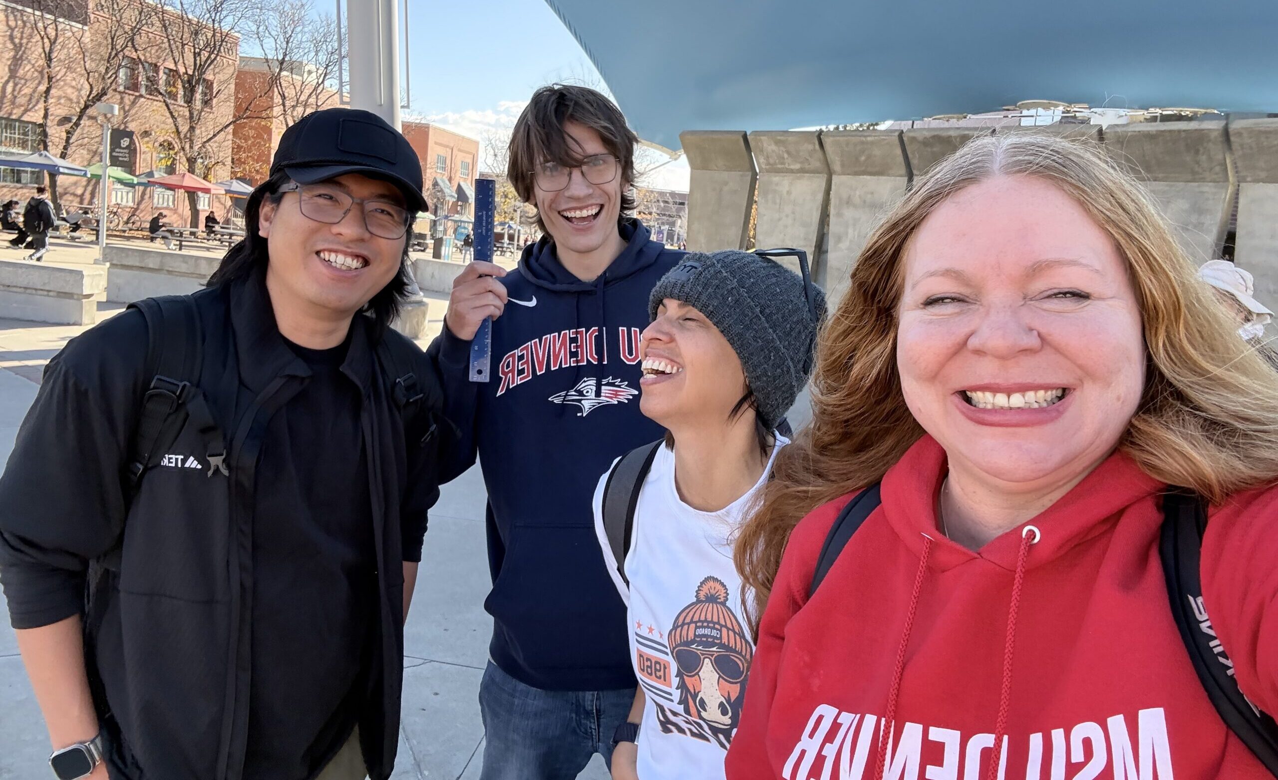 a selfie of four people all smiling at camera standing outside