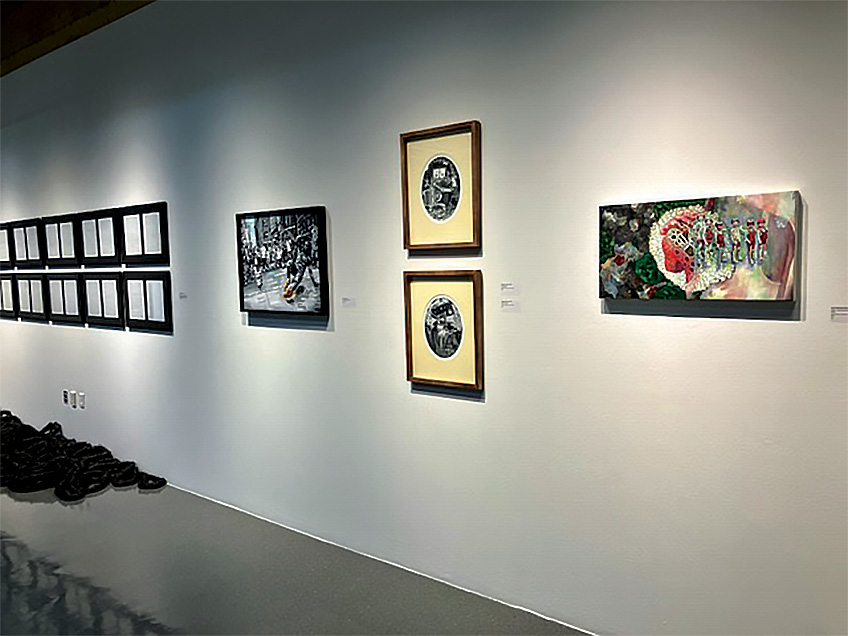 Artworks on a gallery wall, including sketches, a black and white photo, two oval illustrations, and a colorful abstract painting.