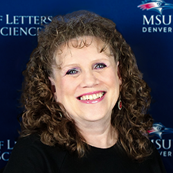 A woman with shoulder-length curly brown hair wearing a black shirt