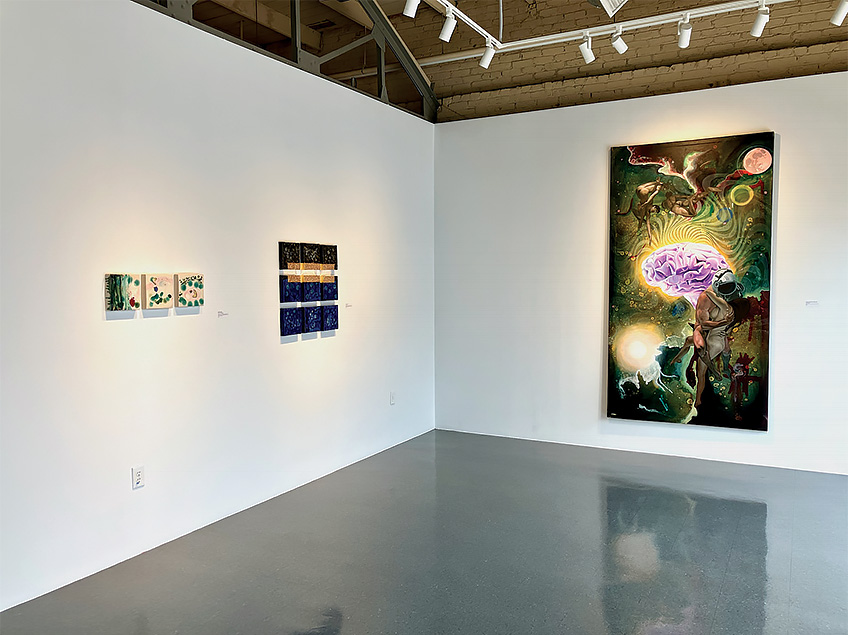 An art gallery room with abstract paintings on white walls and a polished grey floor.