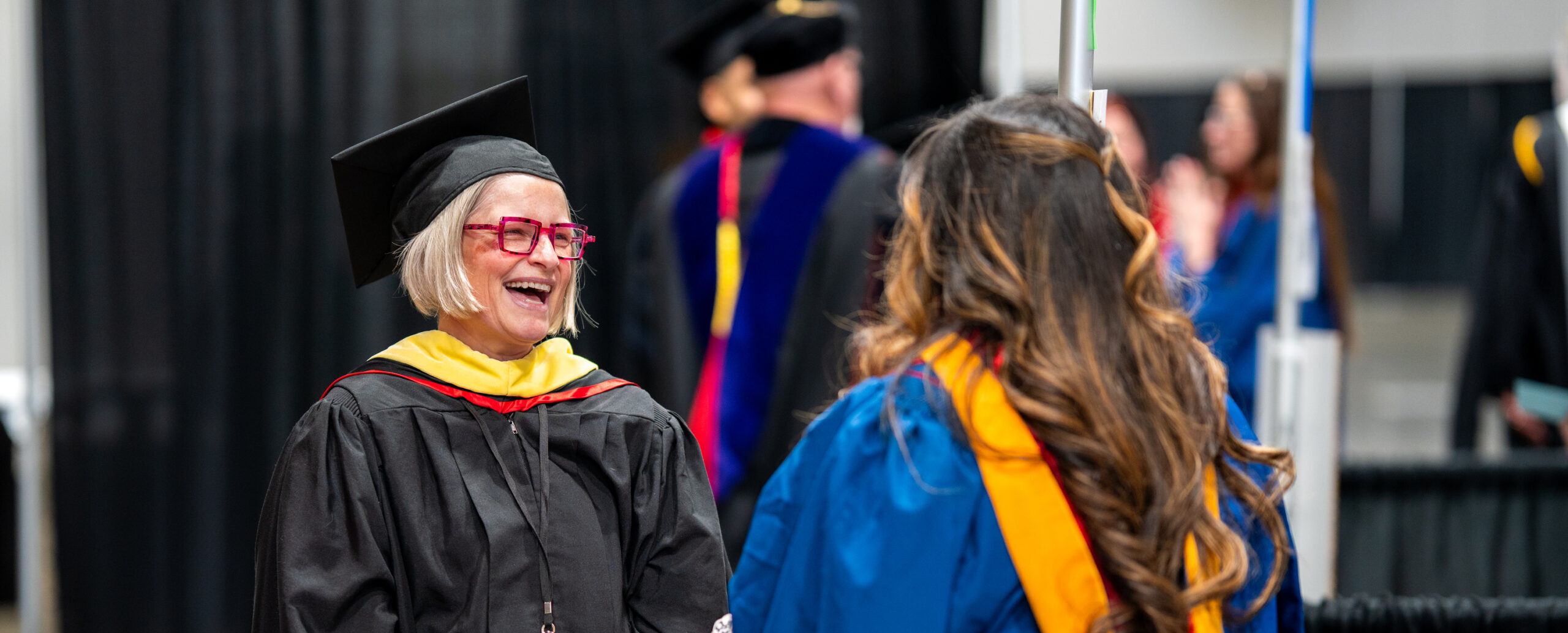 Marshals share excitement with graduates before walking to the commencement floor.