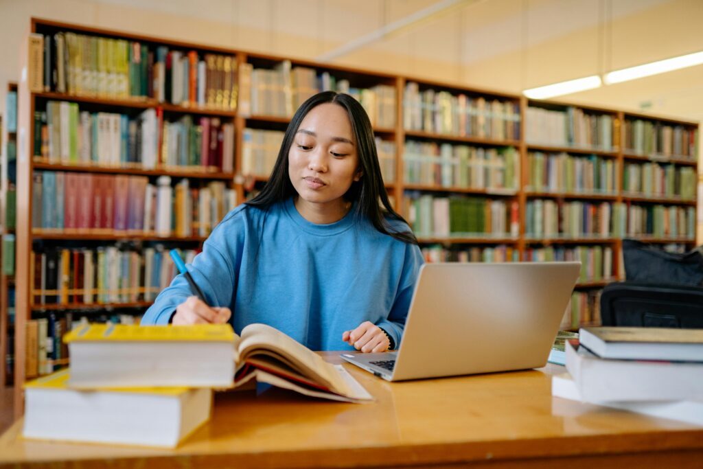Person at a desk with their laptop open and a pen in hand.