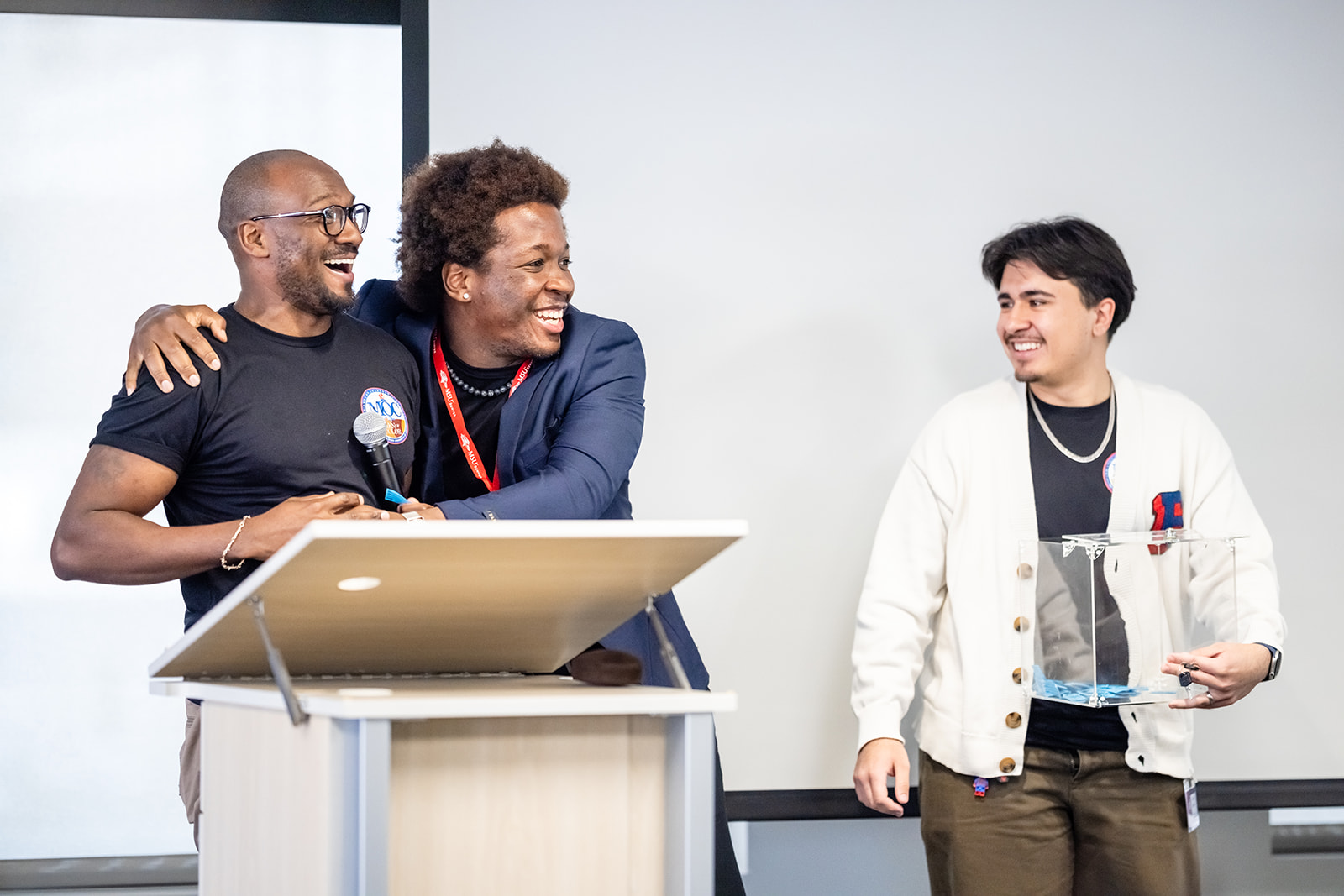 Three people laughing and hugging at event