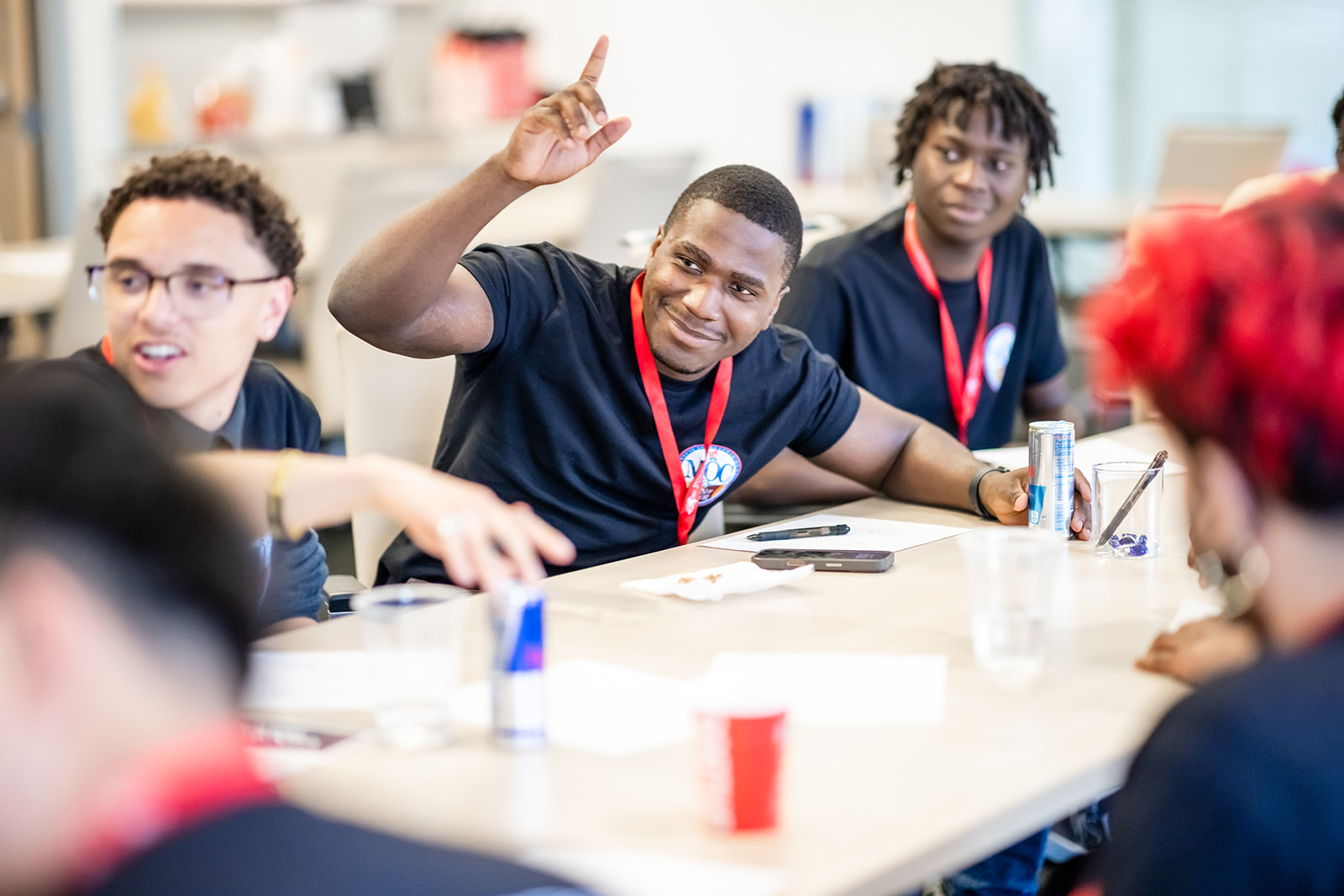 Three students smiling and raising hands during discussion