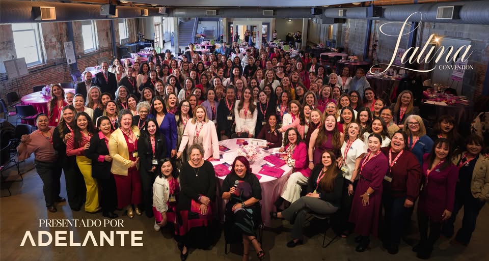 A wide-angle group photo of over 100 smiling women gathered in a large, industrial-style event space at the Tivoli Student Union. Most are looking toward the camera, cheering and celebrating. In the foreground, women are seated around a circular table with pink décor. Text overlays on the image read 