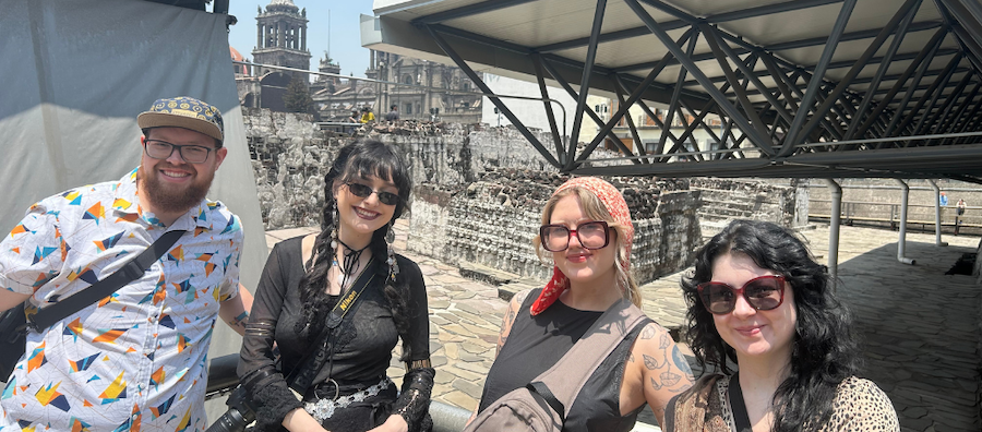 Four people pose for a photo in front of architectural ruins in Mexico.