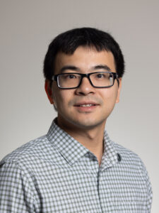 Man in checkered white and grey shirt and wearing glasses