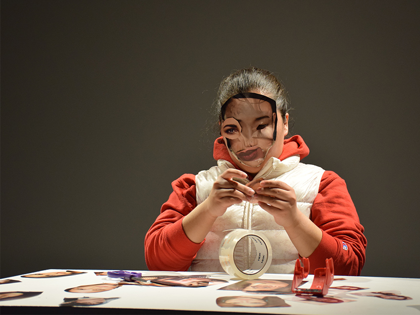 Student covers their own face with facial feature collage from a magazine.