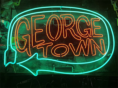 Neon sign that reads Georgetown in red with a green arrow surrounding.