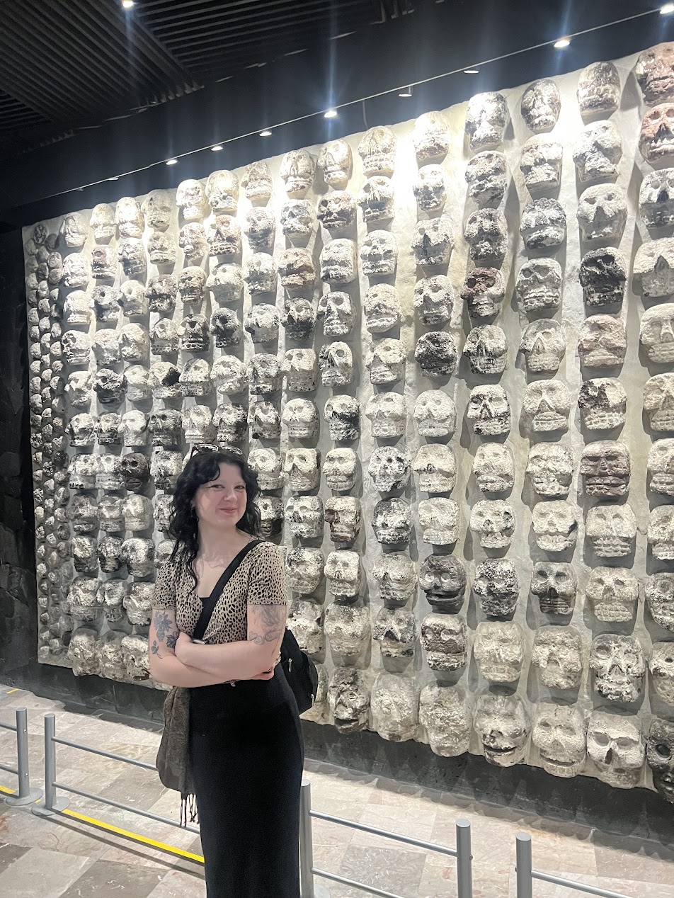 A student in front of a tzompantli (skull rack).
