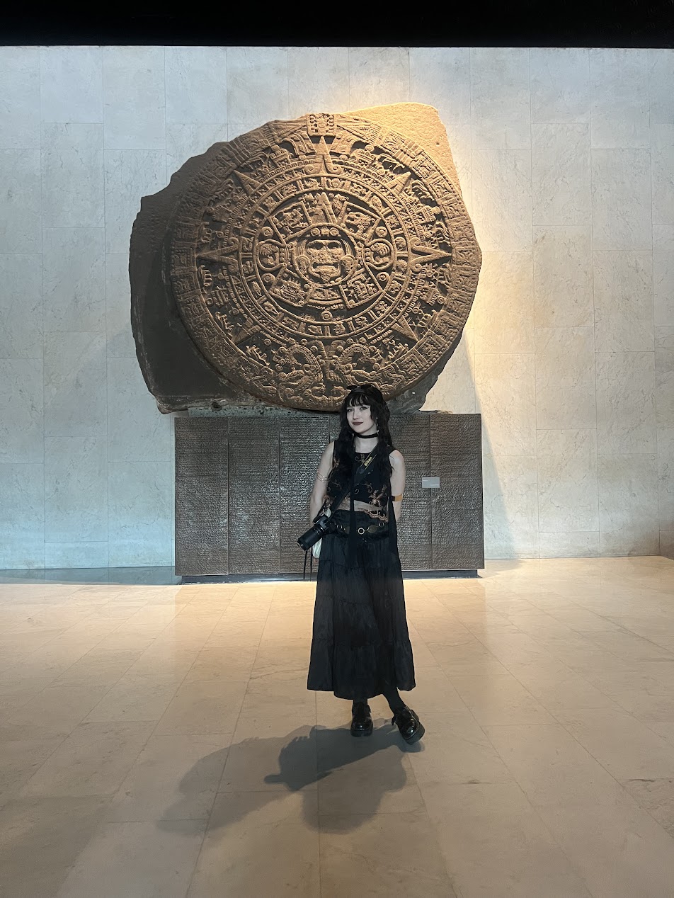 A woman in front of ancient stone artwork.