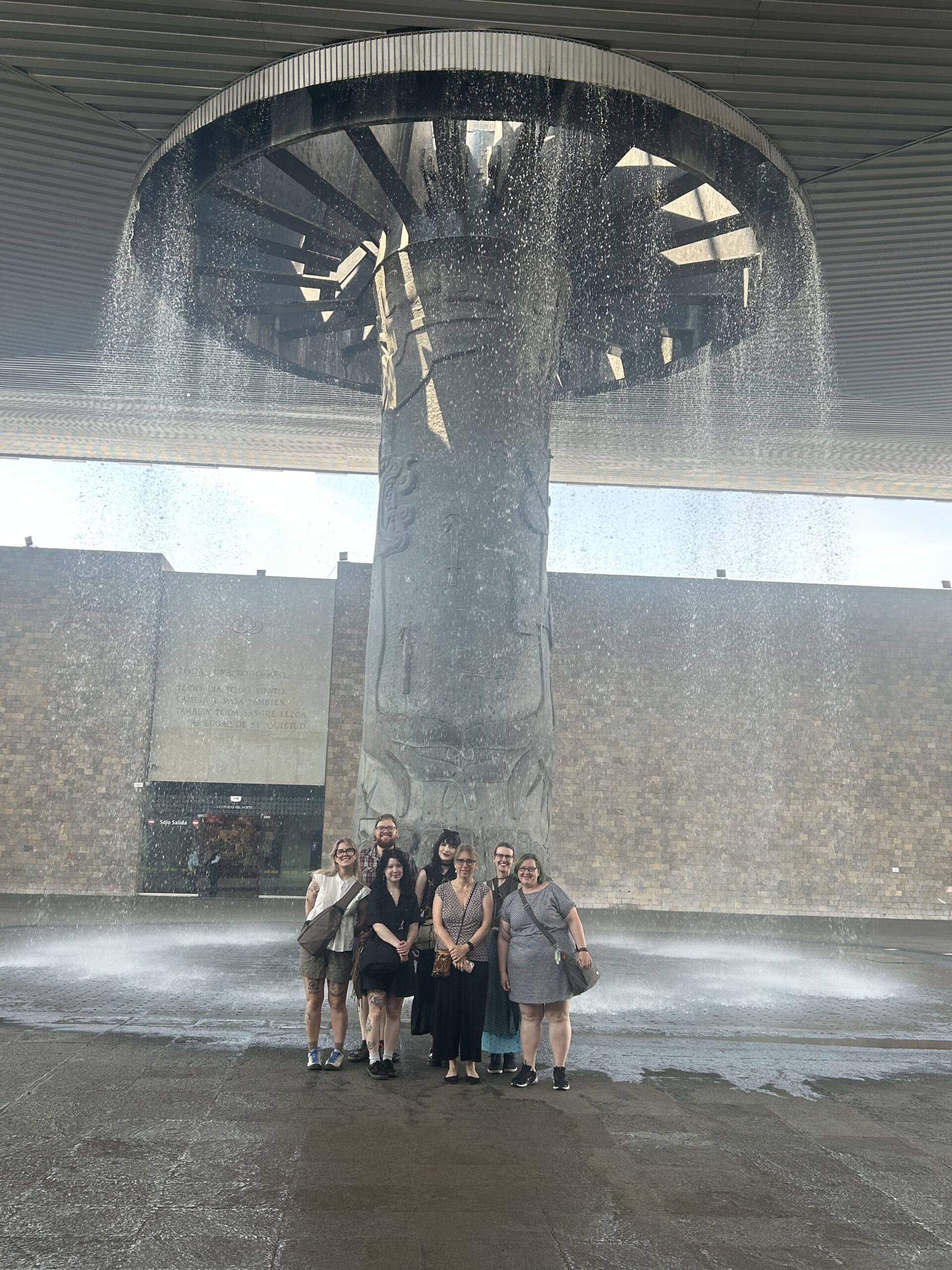 seven people in front of a large fountain.