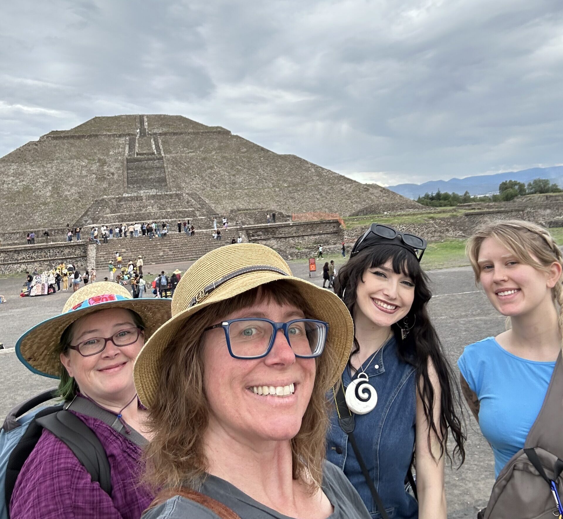 Four people at a pyramid ruins site.