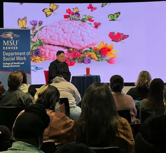 Moderator Bleu Vargas (they/she) sits at the front of the CAVEA Theater, preparing for the keynote with ALOK to begin.
