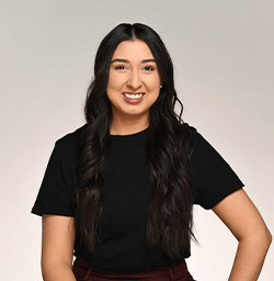 Woman with long dark hair stands in a black tshirt