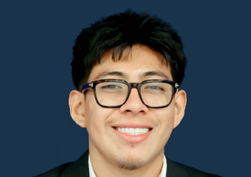 A student wearing glasses, with short black hair, wearing a white collared shirt and a black suit jacket.