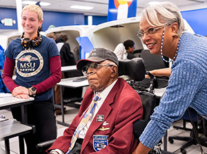 Original Tuskegee Airmen pilot James H. Harvey III, watches students flying simulated aircraft along with his daughter (right) Alysyn Harvey-Green, Computer Information Systems lecturer.