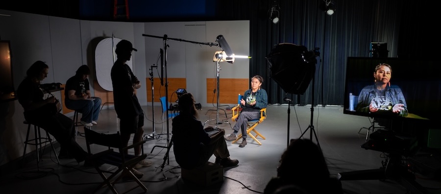 A video recording studio with crew and a woman being interviewed.