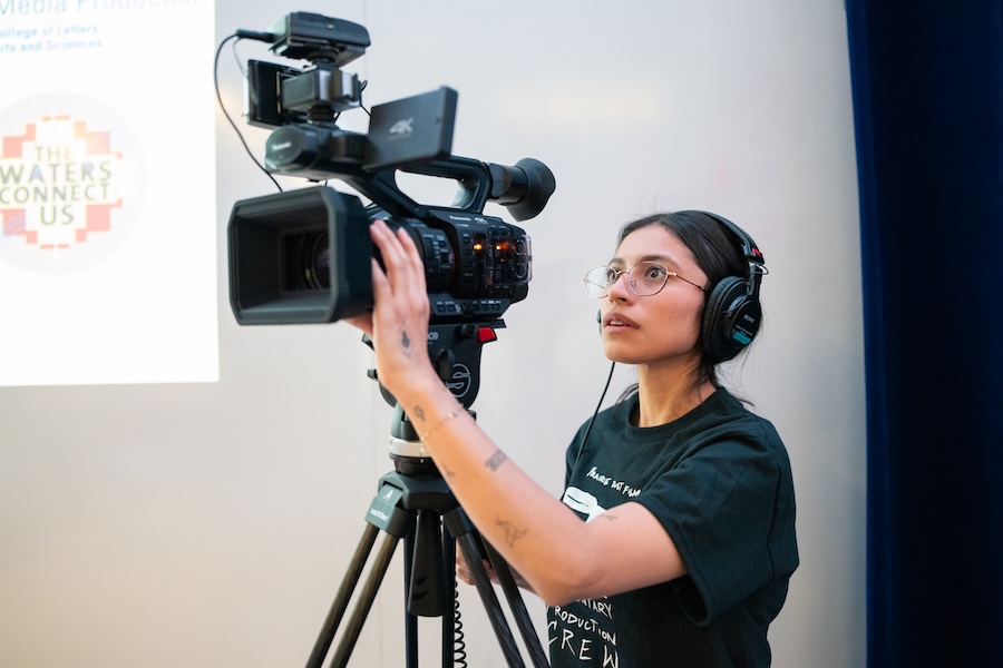 A student angles a large video camera and wears headphones.