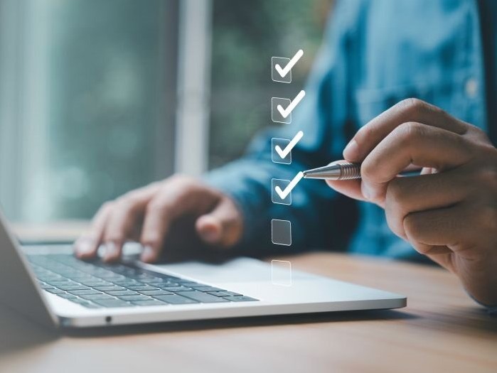 Hands holding a pen mark a check on a list