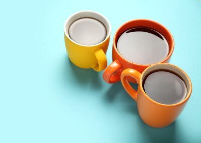 Three full coffee mugs rest against a light blue background