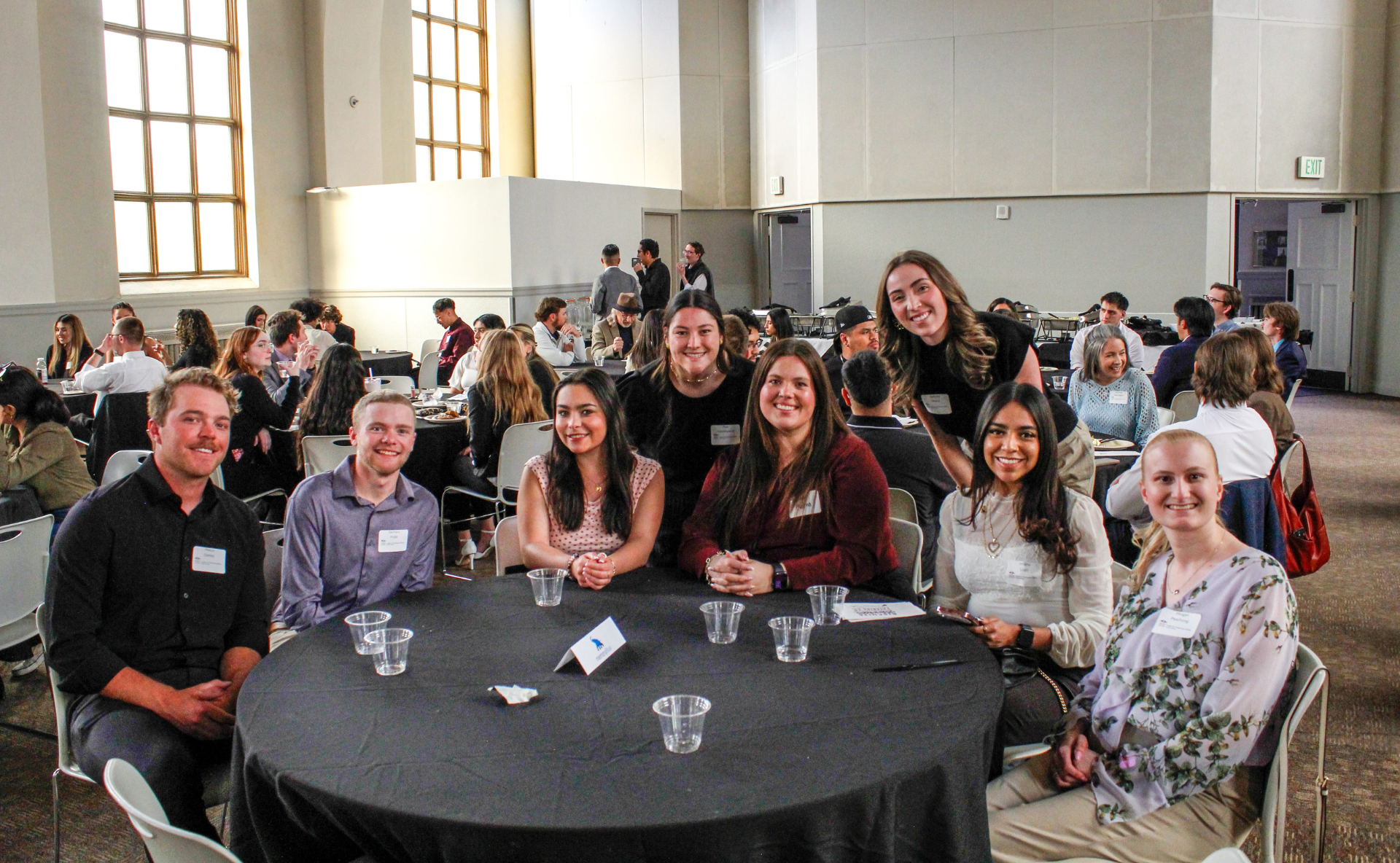 a group of students sitting around a table at the professional selling etiquette dinner