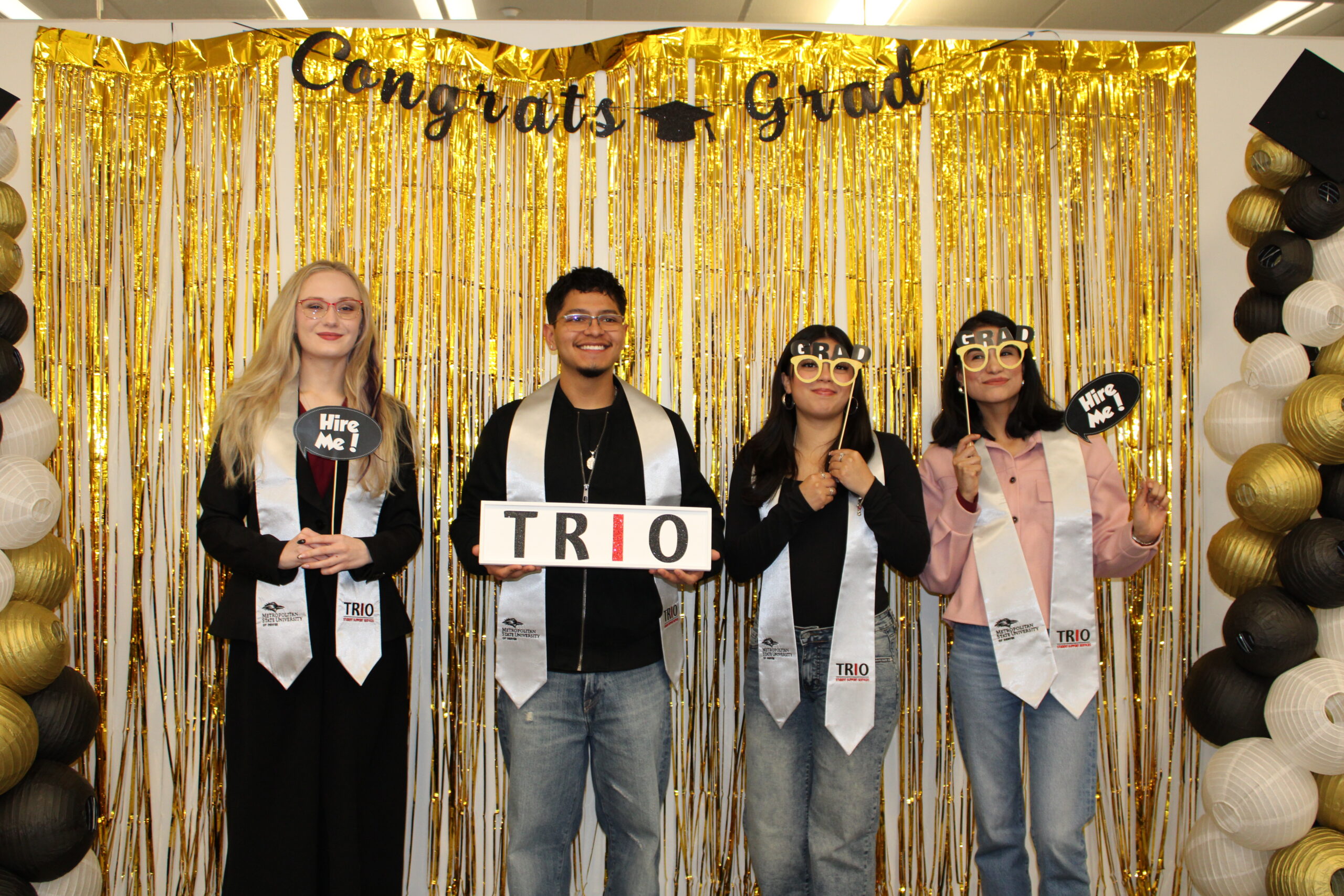 Spring 26 graduates posing for a silly picture and using photobooth props.