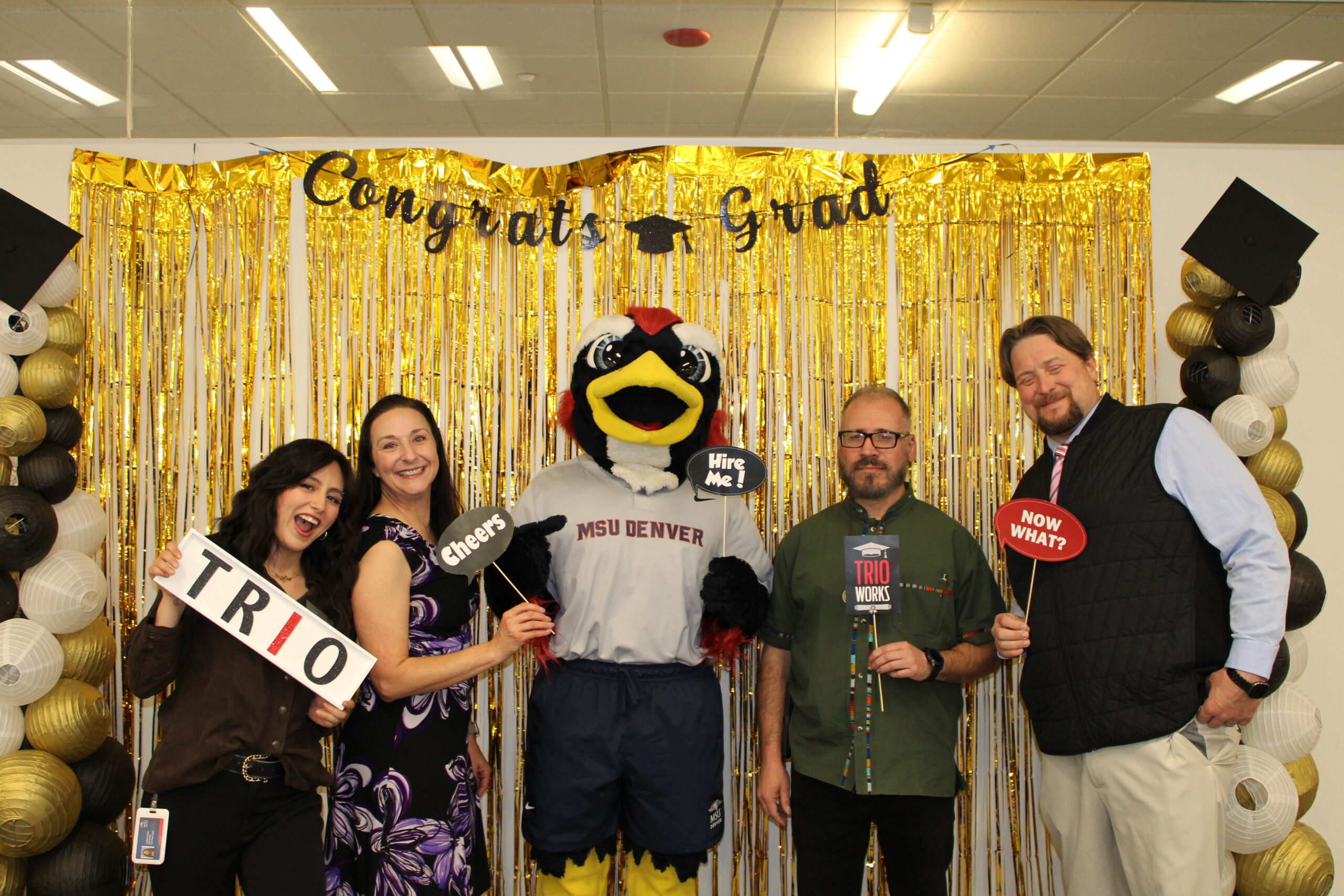 TRIO Staff and Rowdy posing for a picture in front of a gold backdrop