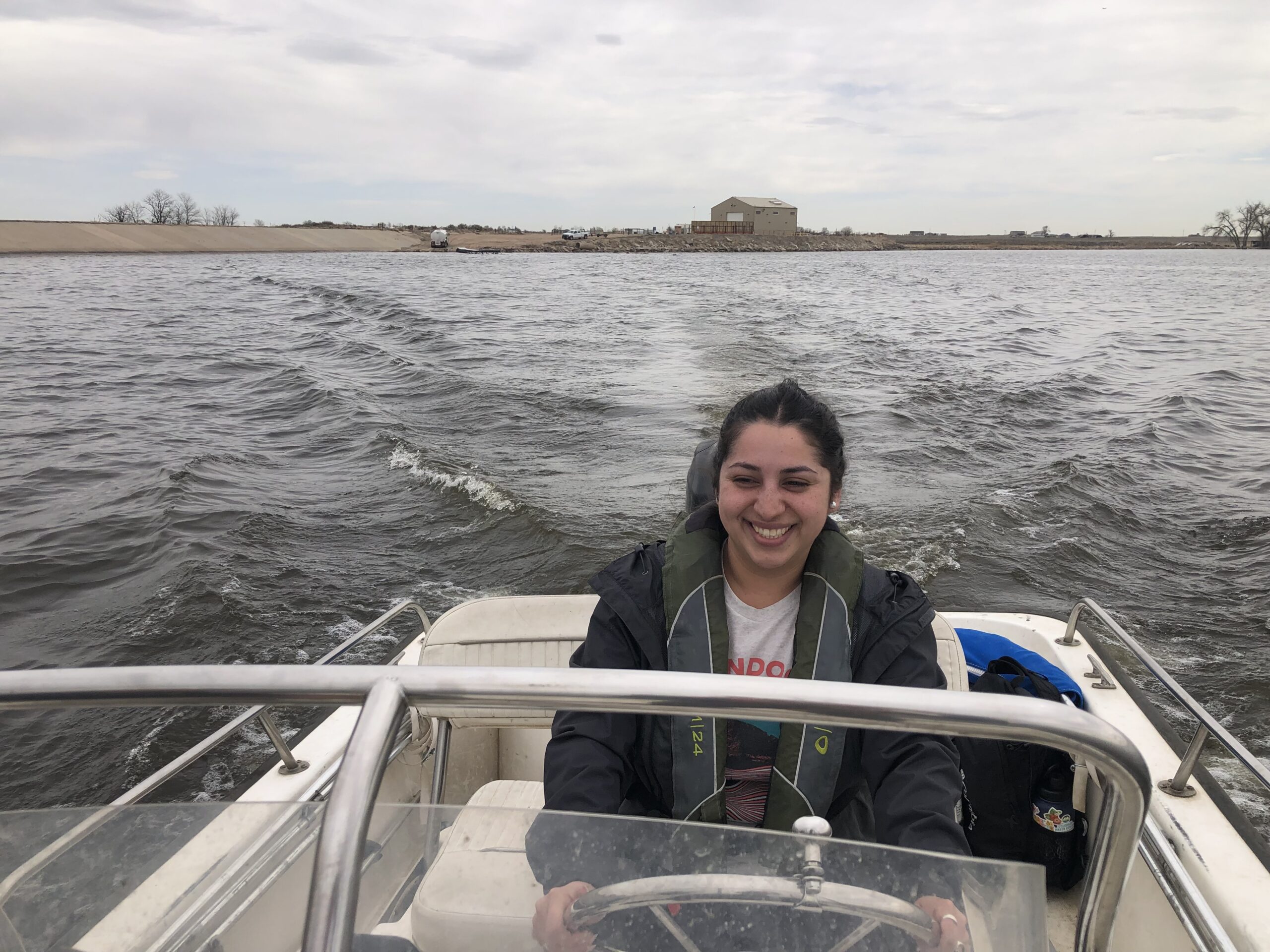 Woman wearing a large coat drives a boat