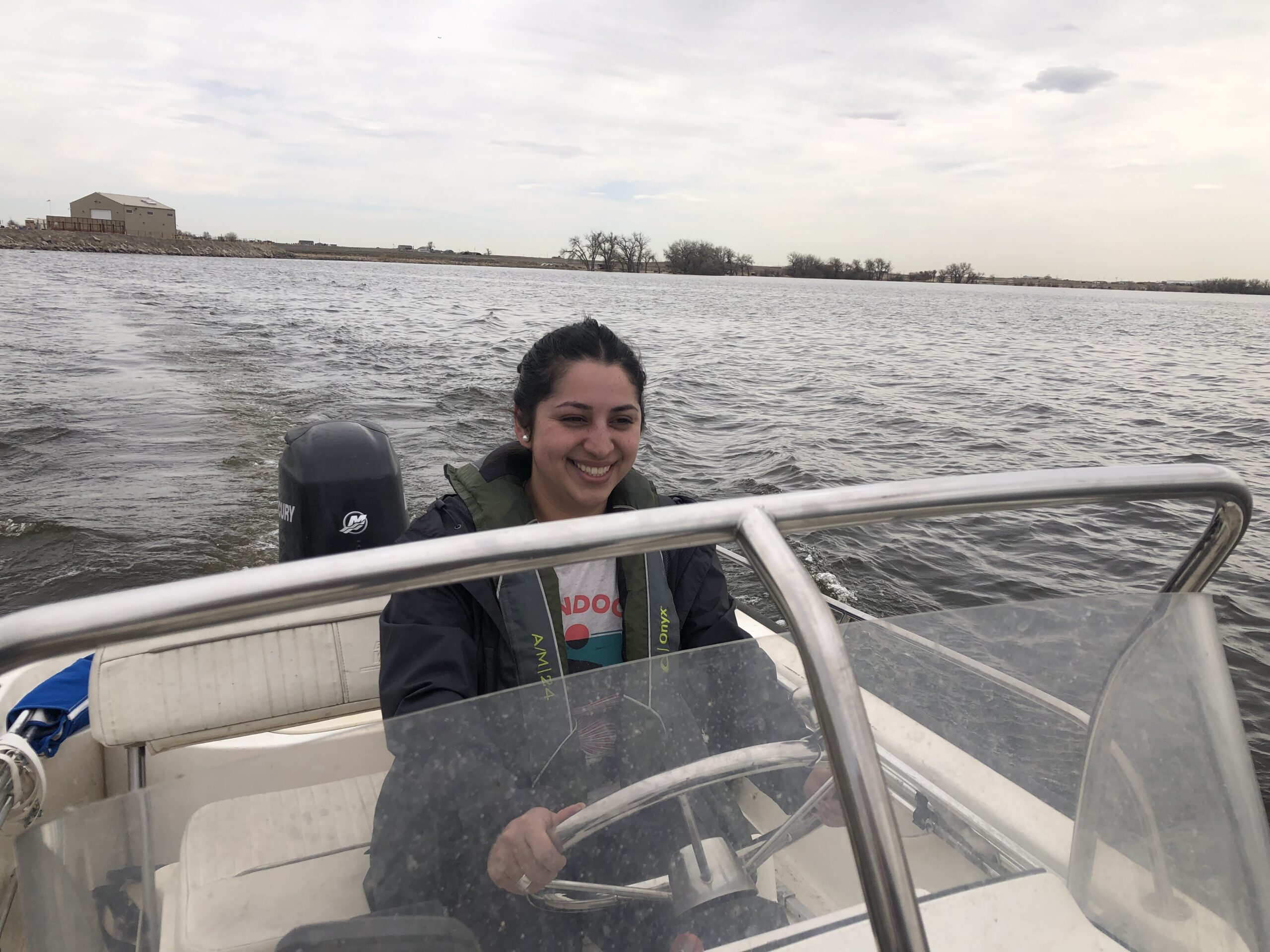Woman wearing a large coat drives a boat