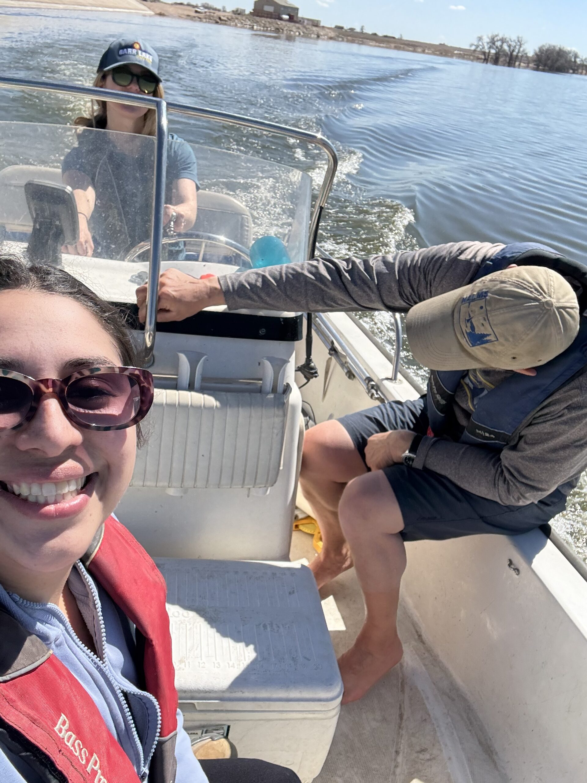Group of people in a boat with a woman smiling in the bottom left corner