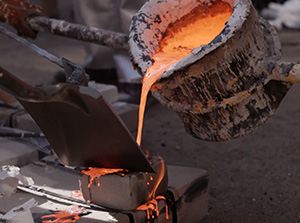 Students pouring molten iron into a sculpture mold