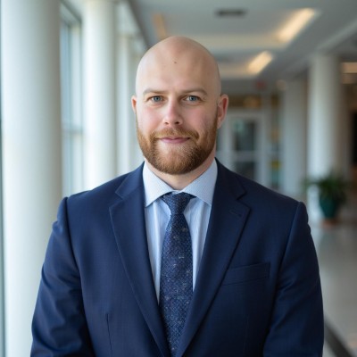 Bearded man in light blue shirt, dark blue tie and dark blue jacket