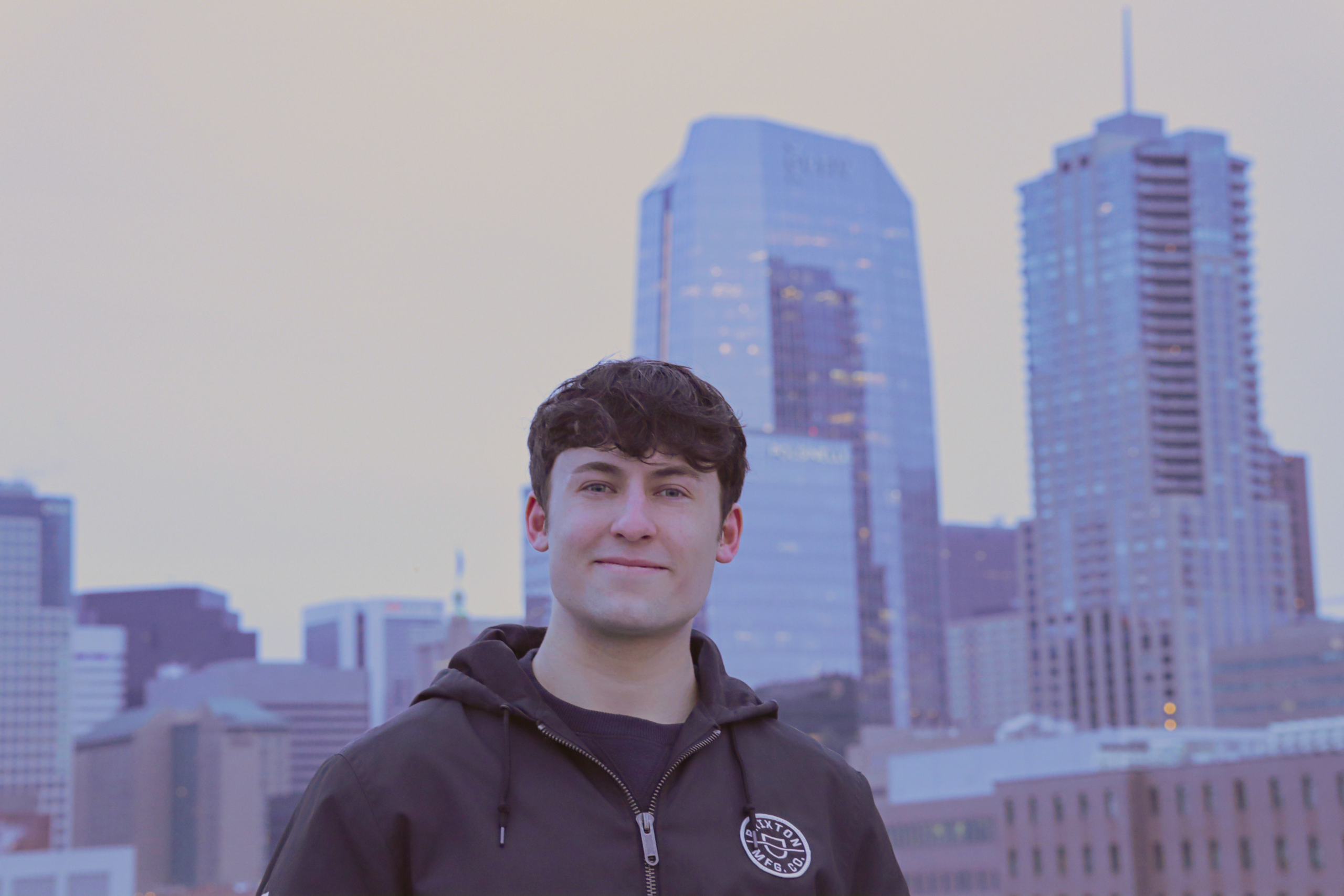 Male student poses for camera with a city backdrop.