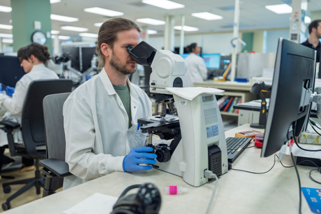 Scientist in a hospital looking at a sample for analysis.