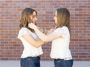 Identical twins Polina, left, and Mariya Giganova fix each other’s hair. Twins run in the family, with their grandfather being one and sister having twins later this summer.