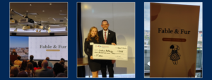A three-panel collage. Left: A student stands at a podium pitching "Fable & Fur." Center: A woman and a man hold a giant ceremonial check for $500 awarded to Sophie Baldwin for 3rd place. Right: A minimalist poster for "Fable & Fur" featuring an illustration of a stuffed animal and the tagline "something worth holding onto."
