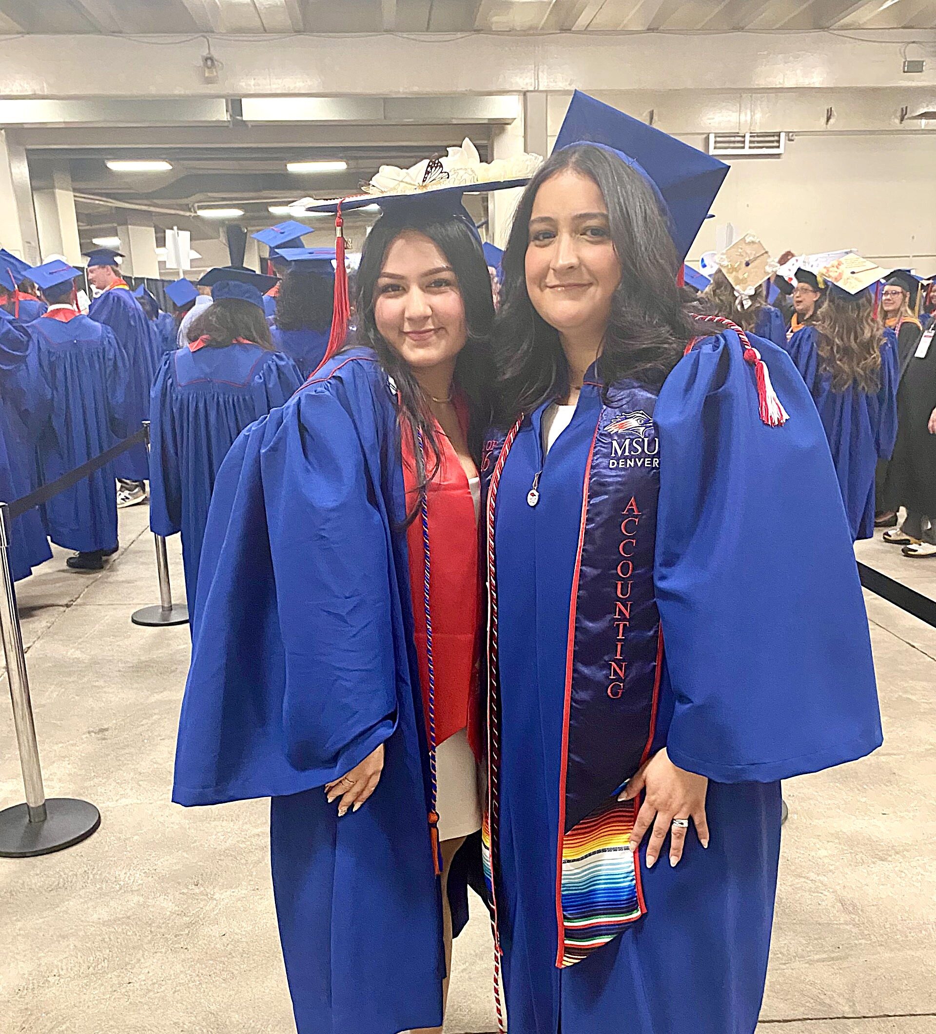 2 accounting grads in regalia smiling backstage before walking into Commencement Ceremony
