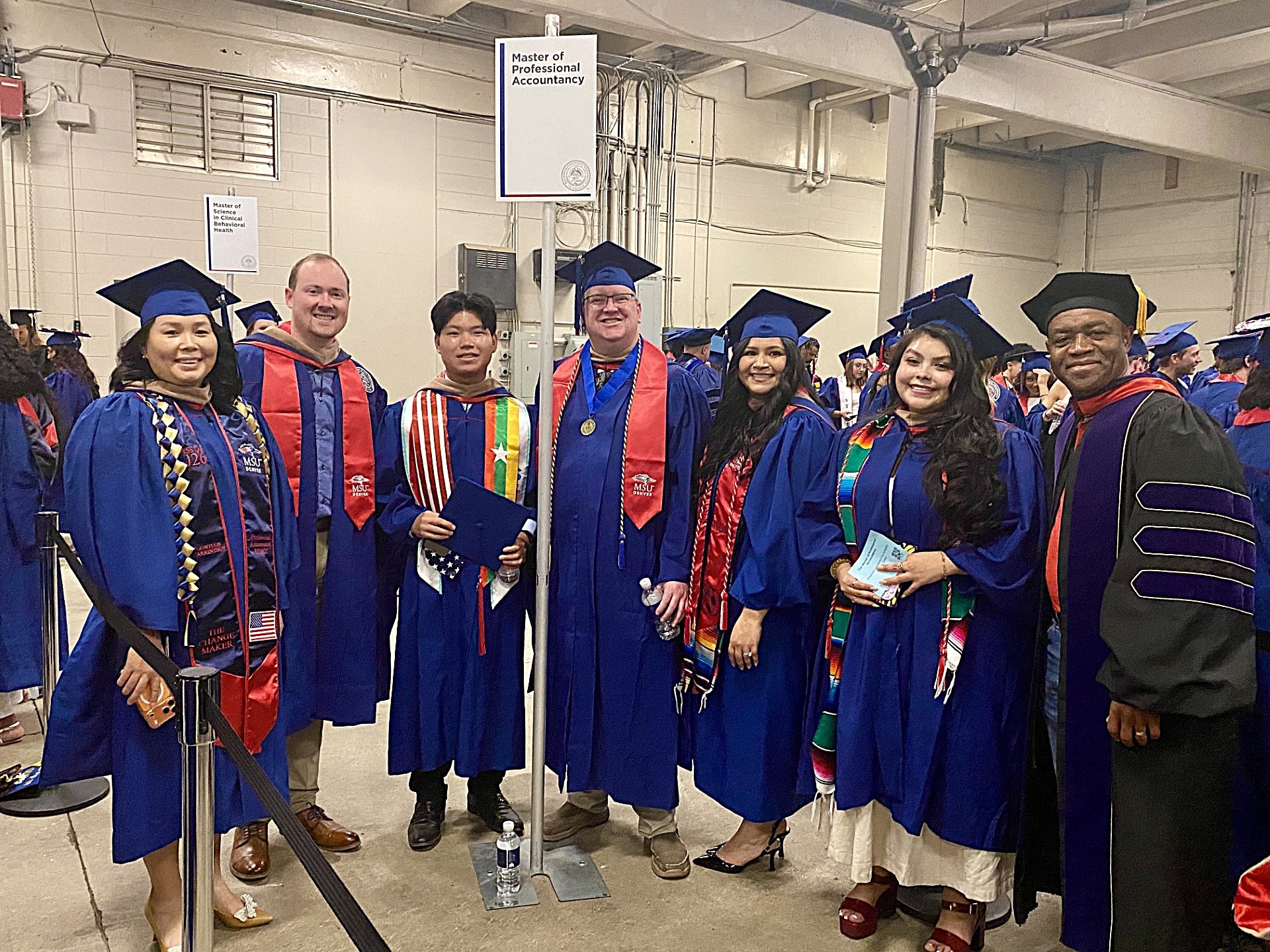 6 MPAcc grads with leadership smiling in regalia before they walk into SP'26 Commencement Ceremony