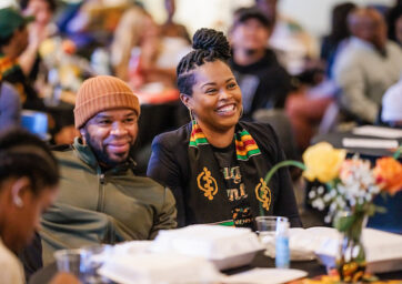 Man and woman sitting next to each other smiling.